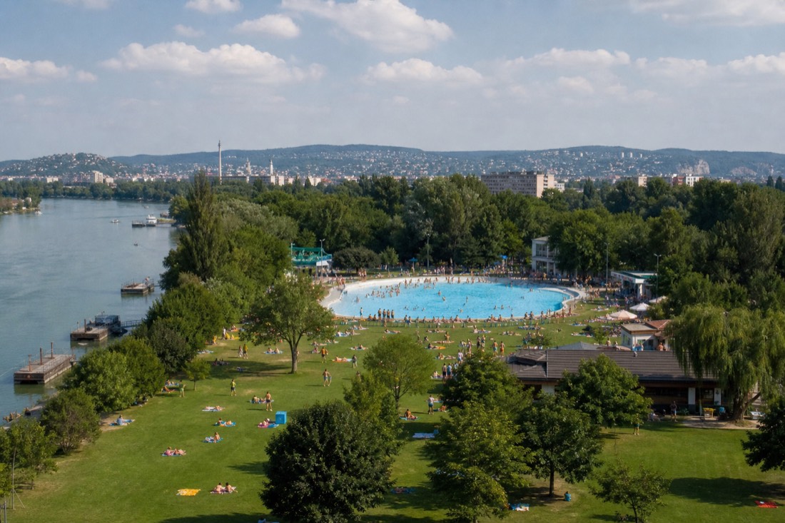 Open-air lido on a leafy Budapest island with lawns, a large pool and families at a distance on a summer afternoon
