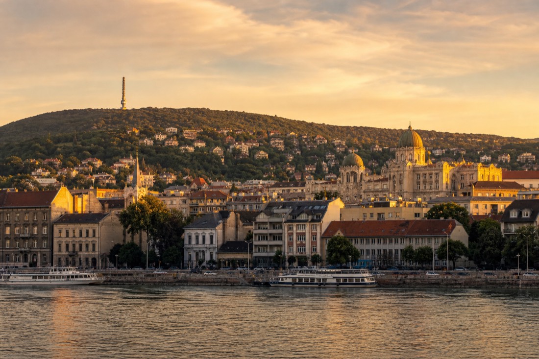 View across the Danube toward the Buda hills at golden hour, where the city's quieter historic baths sit